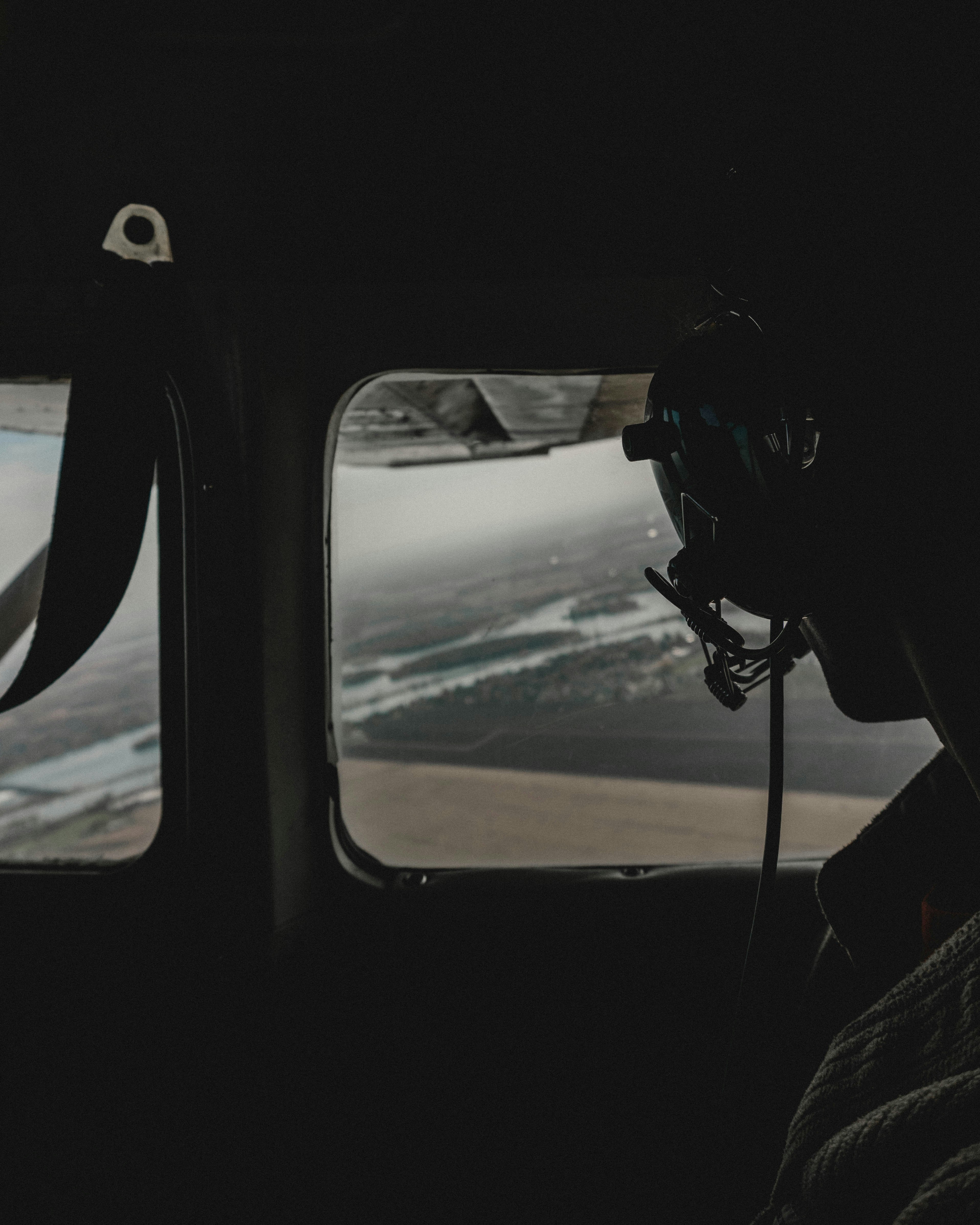 person wearing black headphones inside helicopter while looking down